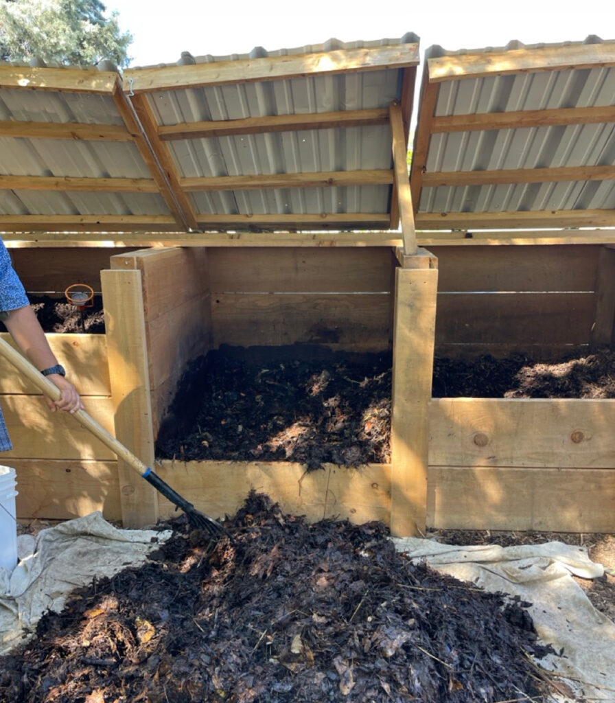 Three compost bins with a compost pile in front