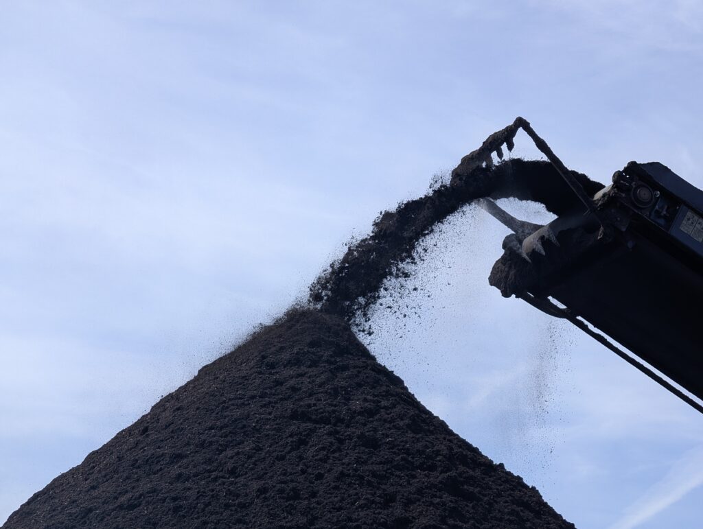 Compost deposited onto a pile by machinery